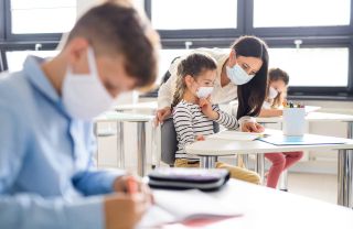 Teacher and kids in classroom with masks.