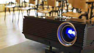 Projector with classroom desks in background.